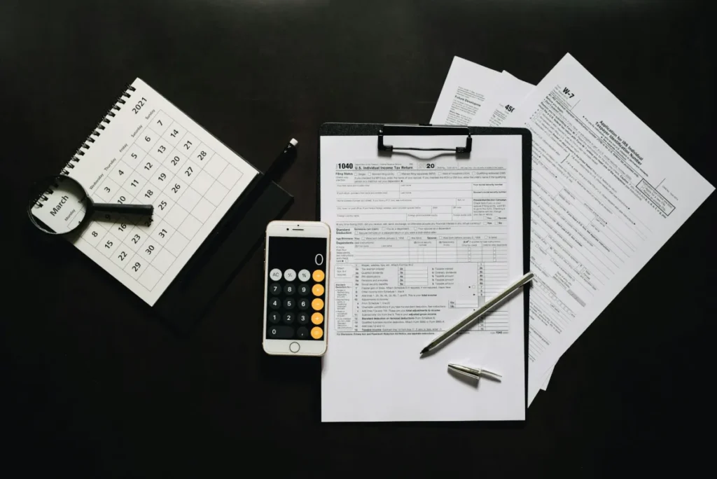 Formulir pajak, kalkulator, dan kalender di atas meja untuk persiapan laporan pajak penghasilan