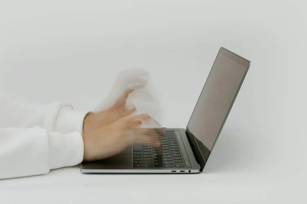 Tangan mengetik cepat di keyboard laptop, menggambarkan pengujian kecepatan internet dan performa jaringan